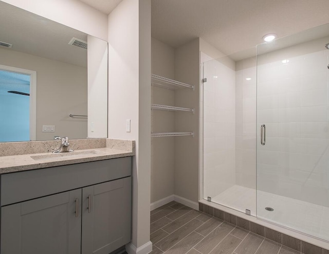 bathroom with a shower with door and vanity