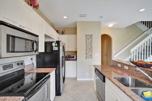 kitchen featuring sink, light tile patterned floors, appliances with stainless steel finishes, light stone countertops, and white cabinets