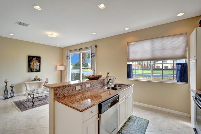 kitchen with sink, light tile patterned floors, stone counters, white cabinetry, and stainless steel dishwasher