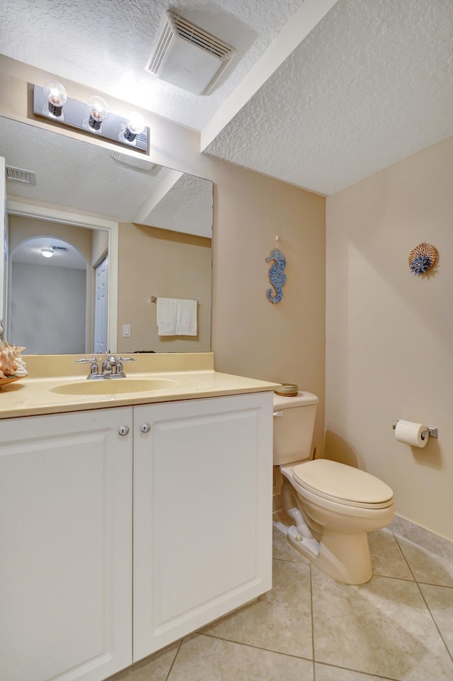 bathroom with vanity, toilet, tile patterned flooring, and a textured ceiling