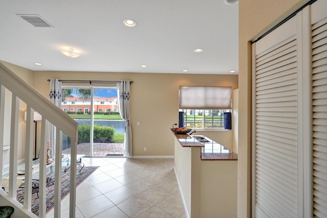 kitchen featuring light tile patterned floors, a water view, and stone counters