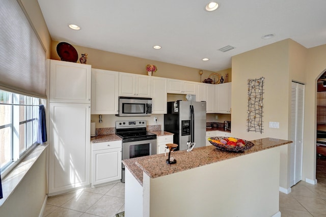 kitchen with appliances with stainless steel finishes, a center island with sink, white cabinets, and light tile patterned floors