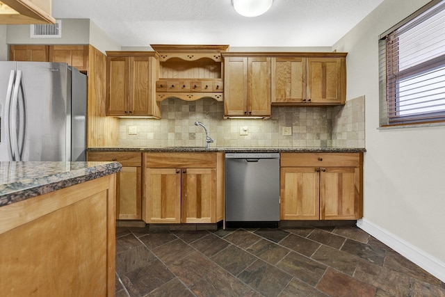 kitchen featuring sink, tasteful backsplash, dark stone counters, and stainless steel appliances