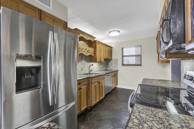 kitchen featuring sink, dark stone counters, a textured ceiling, decorative backsplash, and stainless steel appliances