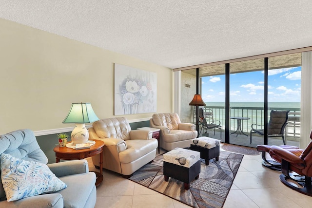 living room with a textured ceiling, tile patterned flooring, a wall of windows, and a water view