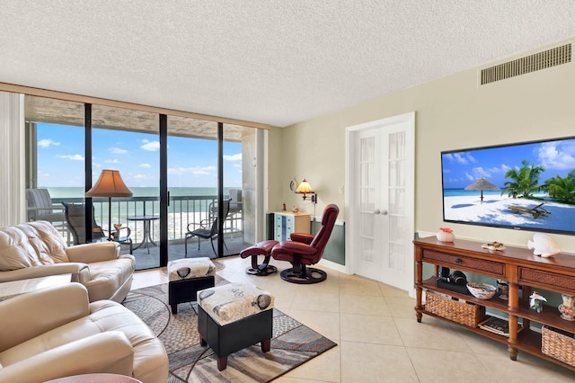 living room with a textured ceiling, light tile patterned floors, and expansive windows