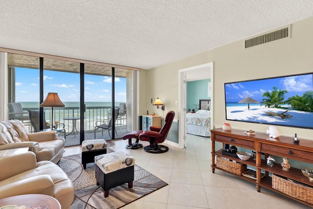 living room featuring a wall of windows, light tile patterned floors, and a textured ceiling