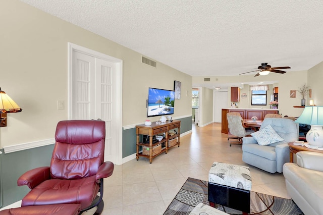 living room with ceiling fan, light tile patterned floors, and a textured ceiling