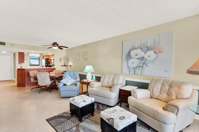 tiled living room with ceiling fan and a textured ceiling