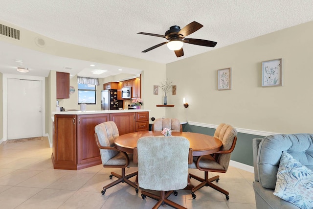 dining room featuring ceiling fan, light tile patterned flooring, and a textured ceiling