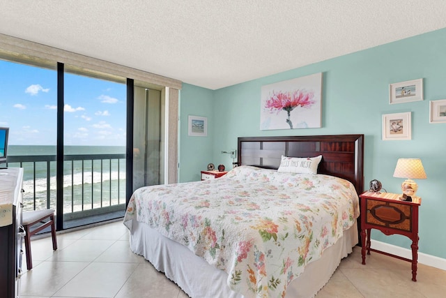 bedroom with a textured ceiling, a wall of windows, a water view, and multiple windows