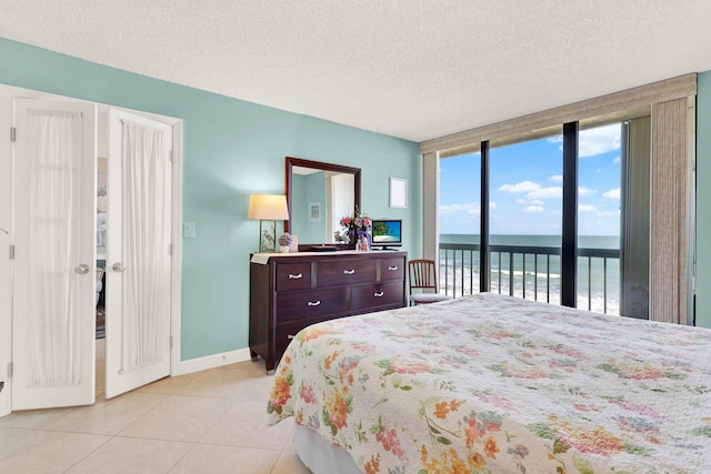 bedroom featuring a textured ceiling, light tile patterned flooring, access to outside, and expansive windows