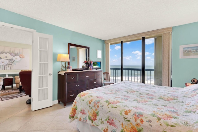 tiled bedroom with a textured ceiling, a wall of windows, and access to outside