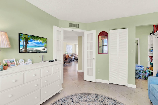 bedroom featuring light tile patterned floors, a closet, and a textured ceiling