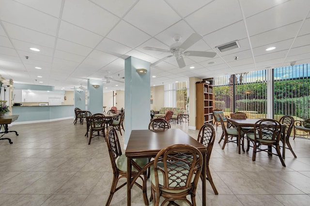 dining area with ceiling fan, a drop ceiling, and expansive windows