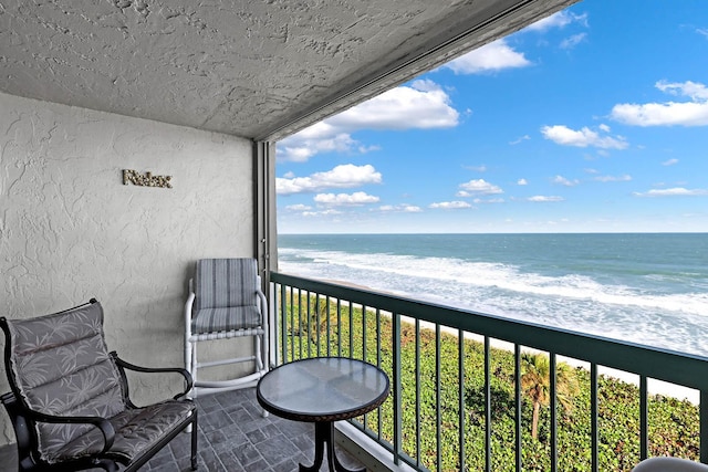 balcony featuring a view of the beach and a water view