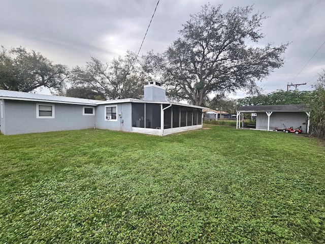 back of property with a sunroom, a carport, and a lawn