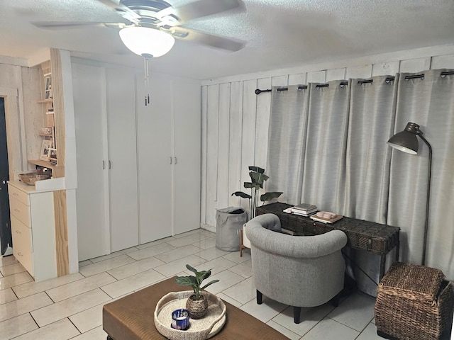 interior space with ceiling fan, wooden walls, and a textured ceiling