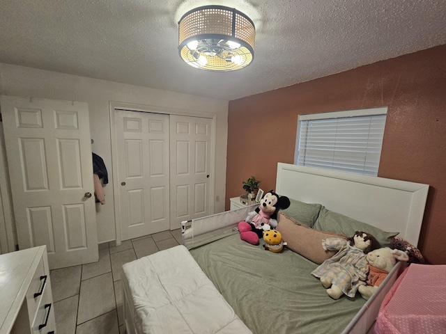 bedroom featuring a textured ceiling, a closet, and light tile patterned flooring