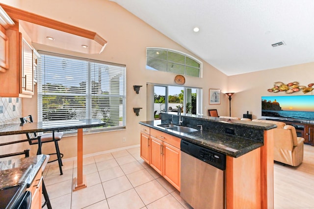 kitchen with sink, light tile patterned floors, a kitchen island with sink, dark stone countertops, and stainless steel dishwasher