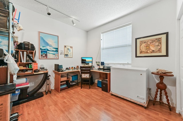 office with rail lighting, a textured ceiling, and light wood-type flooring