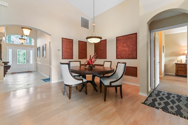 dining room featuring high vaulted ceiling and light wood-type flooring