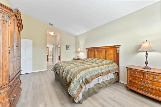 bedroom with vaulted ceiling, ensuite bathroom, a textured ceiling, and light wood-type flooring