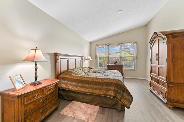 bedroom featuring lofted ceiling, wood-type flooring, and a textured ceiling