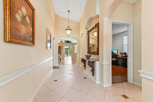 hall featuring a high ceiling and light tile patterned flooring