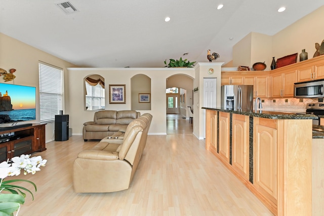 living room featuring lofted ceiling, sink, and light hardwood / wood-style flooring