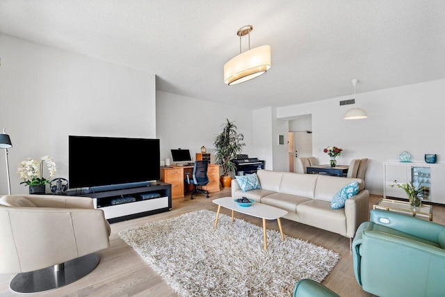 living room featuring a textured ceiling and light wood-type flooring