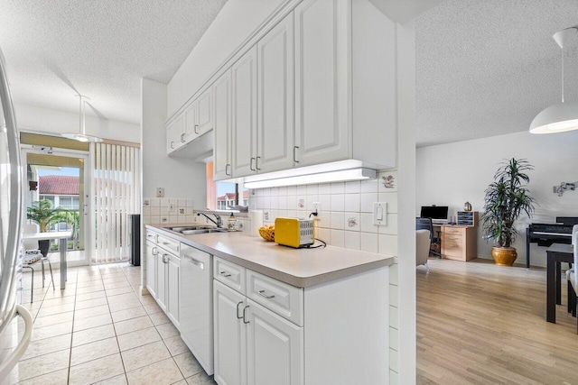 kitchen with backsplash, white dishwasher, sink, and white cabinets