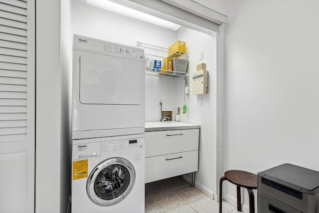 washroom featuring light tile patterned flooring and stacked washing maching and dryer