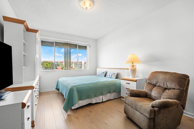 bedroom with a textured ceiling and light wood-type flooring