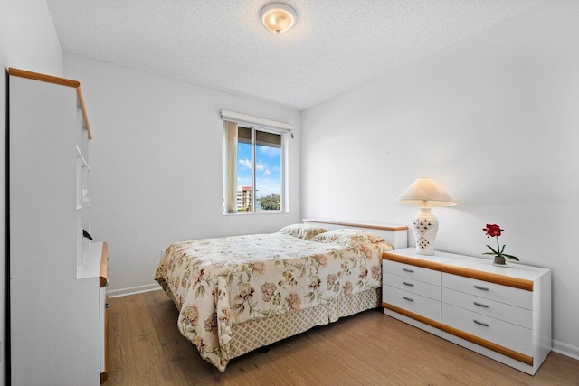 bedroom with a textured ceiling and light wood-type flooring