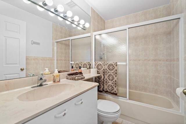 full bathroom featuring tile walls, vanity, bath / shower combo with glass door, and toilet