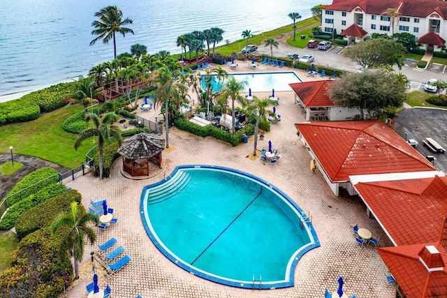 view of swimming pool featuring a water view and a patio