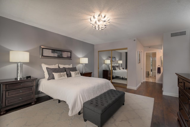 bedroom with hardwood / wood-style floors, connected bathroom, a chandelier, a textured ceiling, and a closet