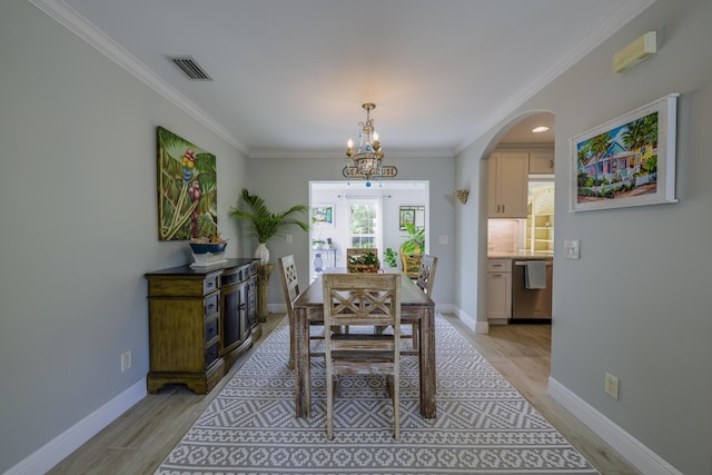 dining space featuring light hardwood / wood-style floors, crown molding, and a notable chandelier