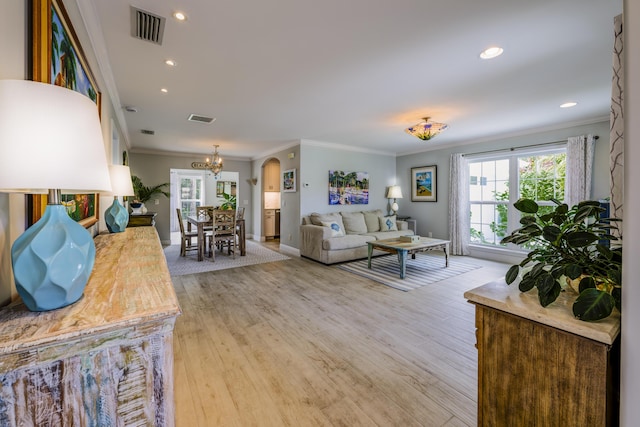 living room with light wood-type flooring, a notable chandelier, and ornamental molding