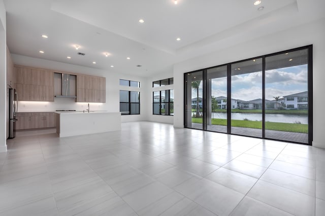 unfurnished living room with sink, a water view, and light tile patterned floors