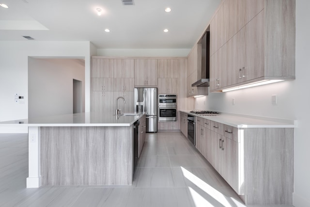 kitchen with sink, light brown cabinets, wall chimney exhaust hood, and a spacious island