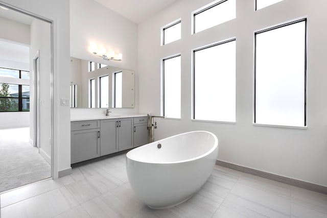 bathroom with a washtub, vanity, and tile patterned flooring