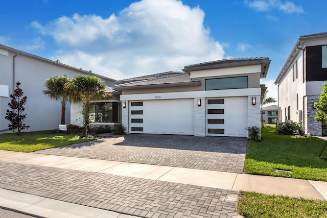 prairie-style house featuring a garage and a front lawn