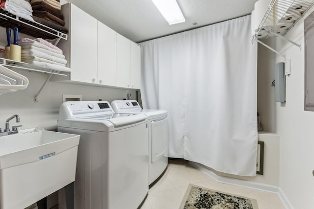 laundry room with cabinets, light tile patterned floors, sink, and washing machine and clothes dryer