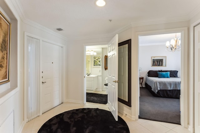 tiled foyer entrance with ornamental molding, a chandelier, and sink