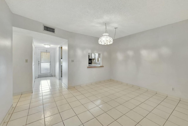 unfurnished room featuring a textured ceiling and light tile patterned floors