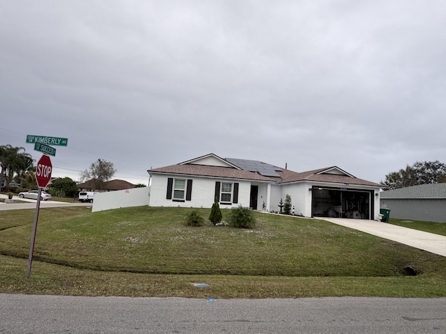 ranch-style house with a front yard, a garage, and solar panels