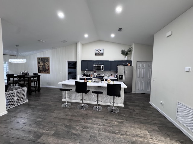 kitchen featuring lofted ceiling, a center island with sink, a kitchen bar, sink, and stainless steel appliances