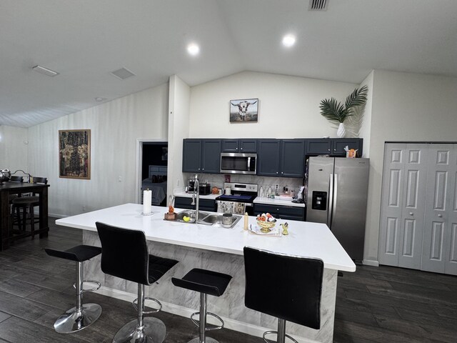 kitchen featuring appliances with stainless steel finishes, sink, backsplash, a breakfast bar, and a center island with sink